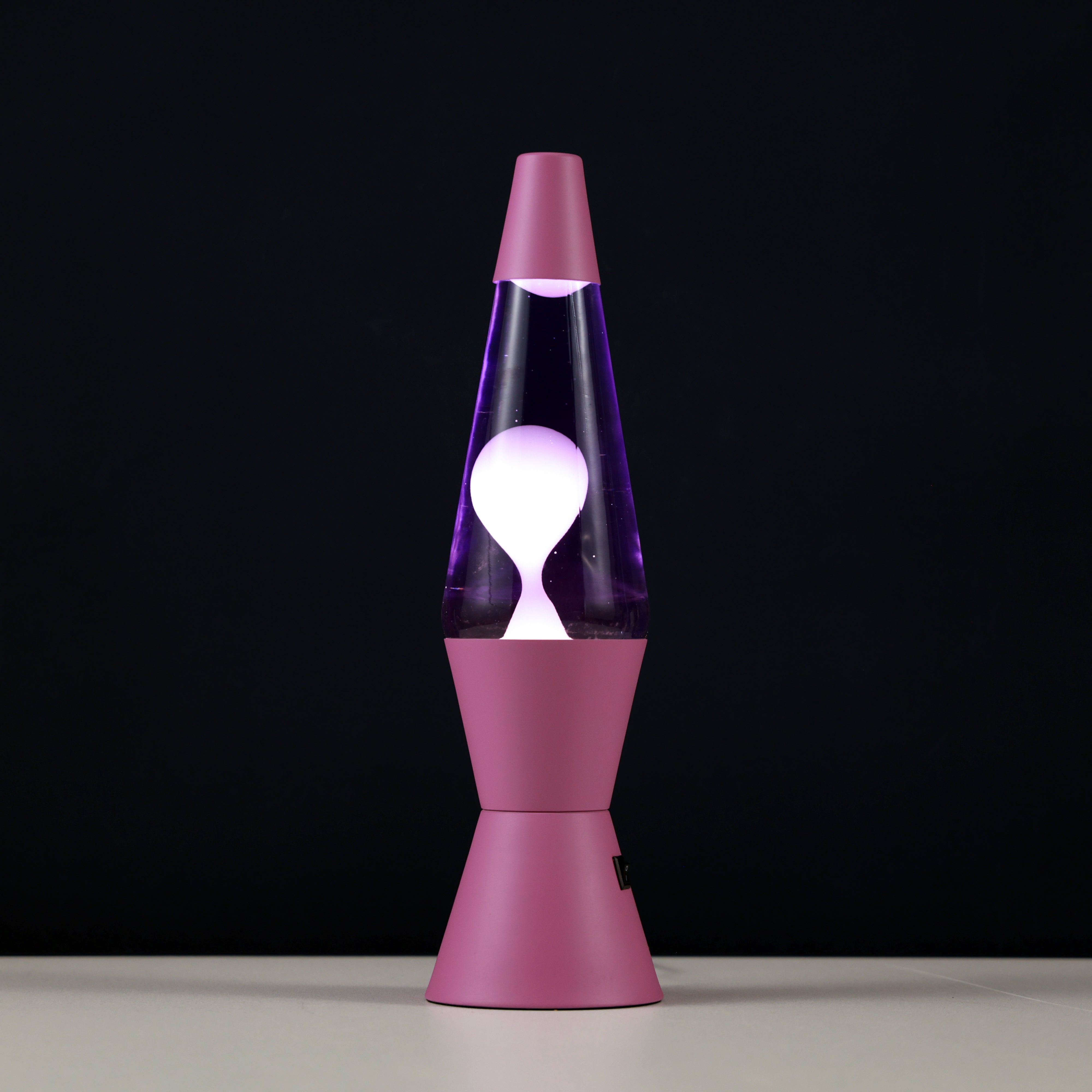 Leuchtende iTotal LED Lavalampe Spaceship mit rosa Gehäuse und violett schimmernden, aufsteigenden Wachsblasen vor schwarzem Hintergrund.
