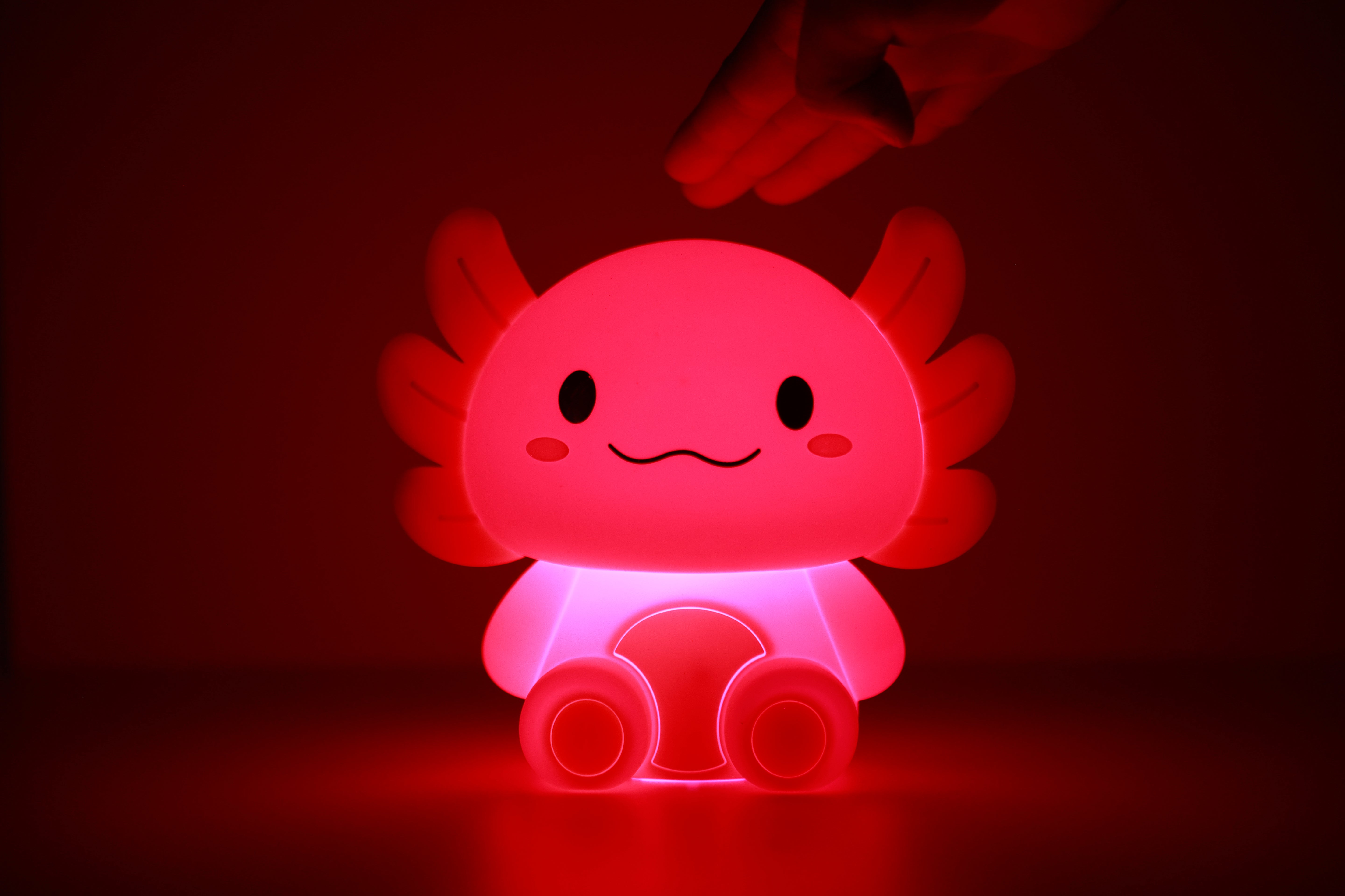Rosa leuchtendes iTotal Axolotl-Nachtlicht aus Silikon in dunkler Umgebung.