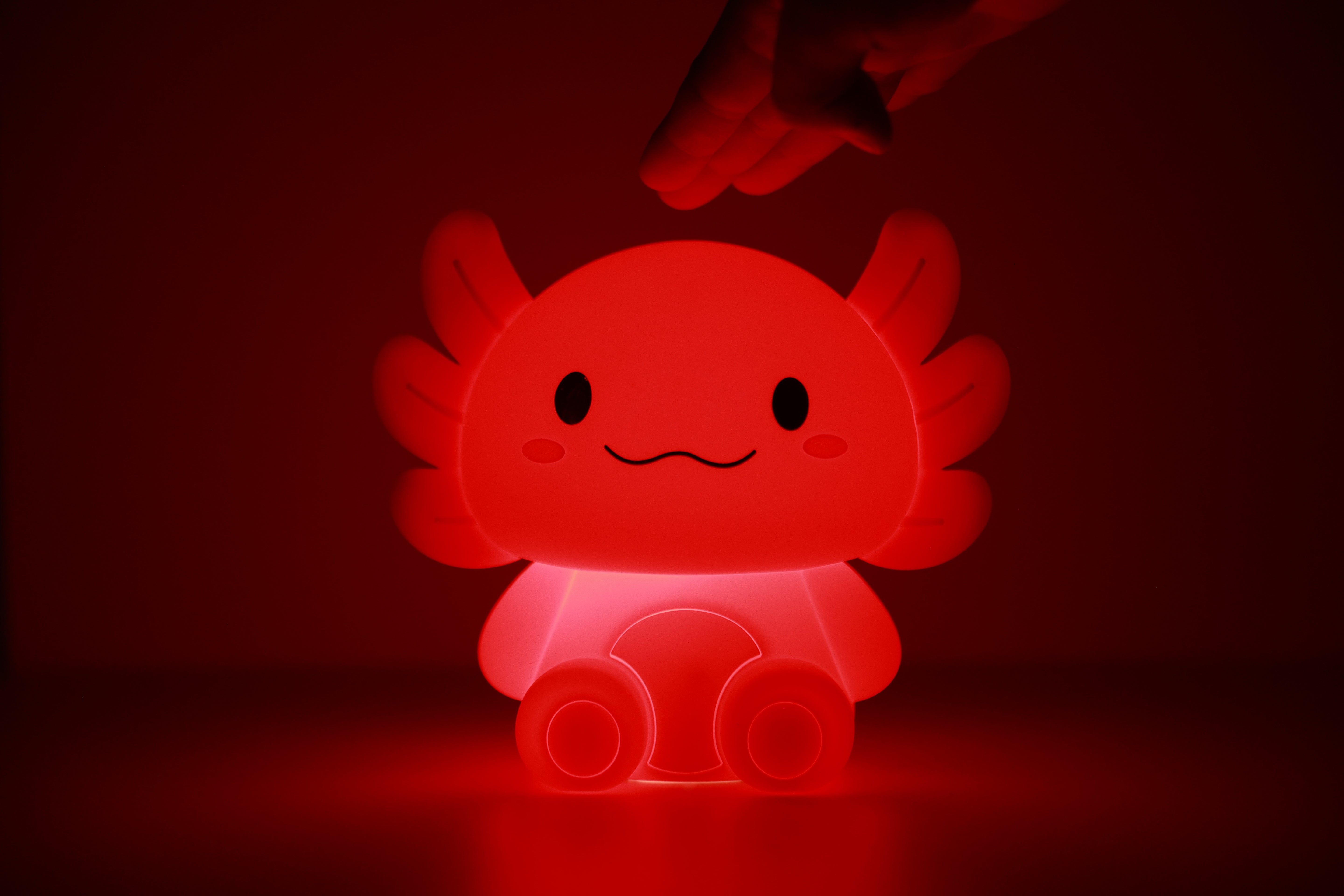 Rosa leuchtendes iTotal Axolotl-Nachtlicht aus Silikon in dunkler Umgebung.
