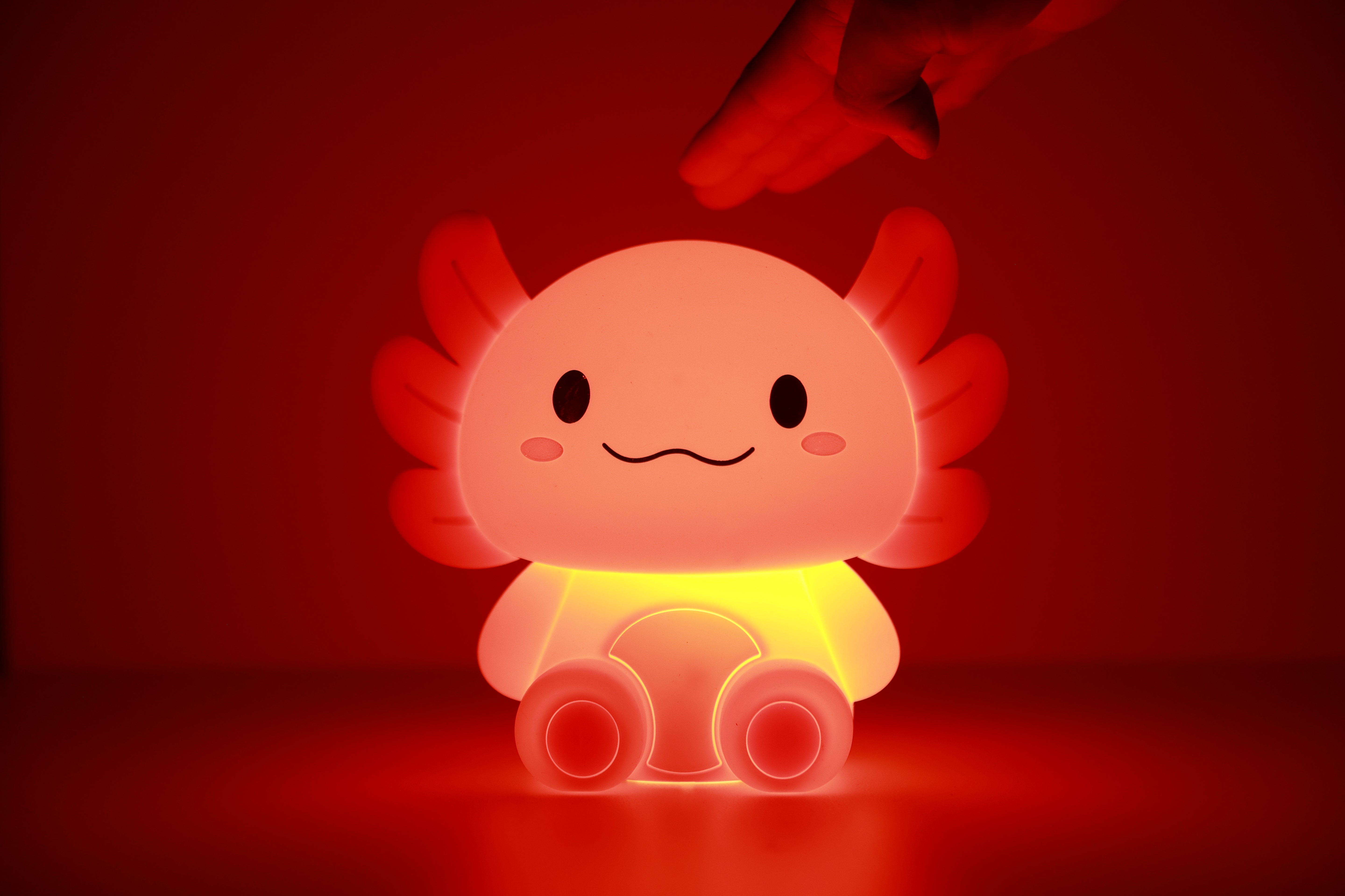 Gelb-orange leuchtendes iTotal Axolotl-Nachtlicht aus Silikon in dunkler Umgebung.