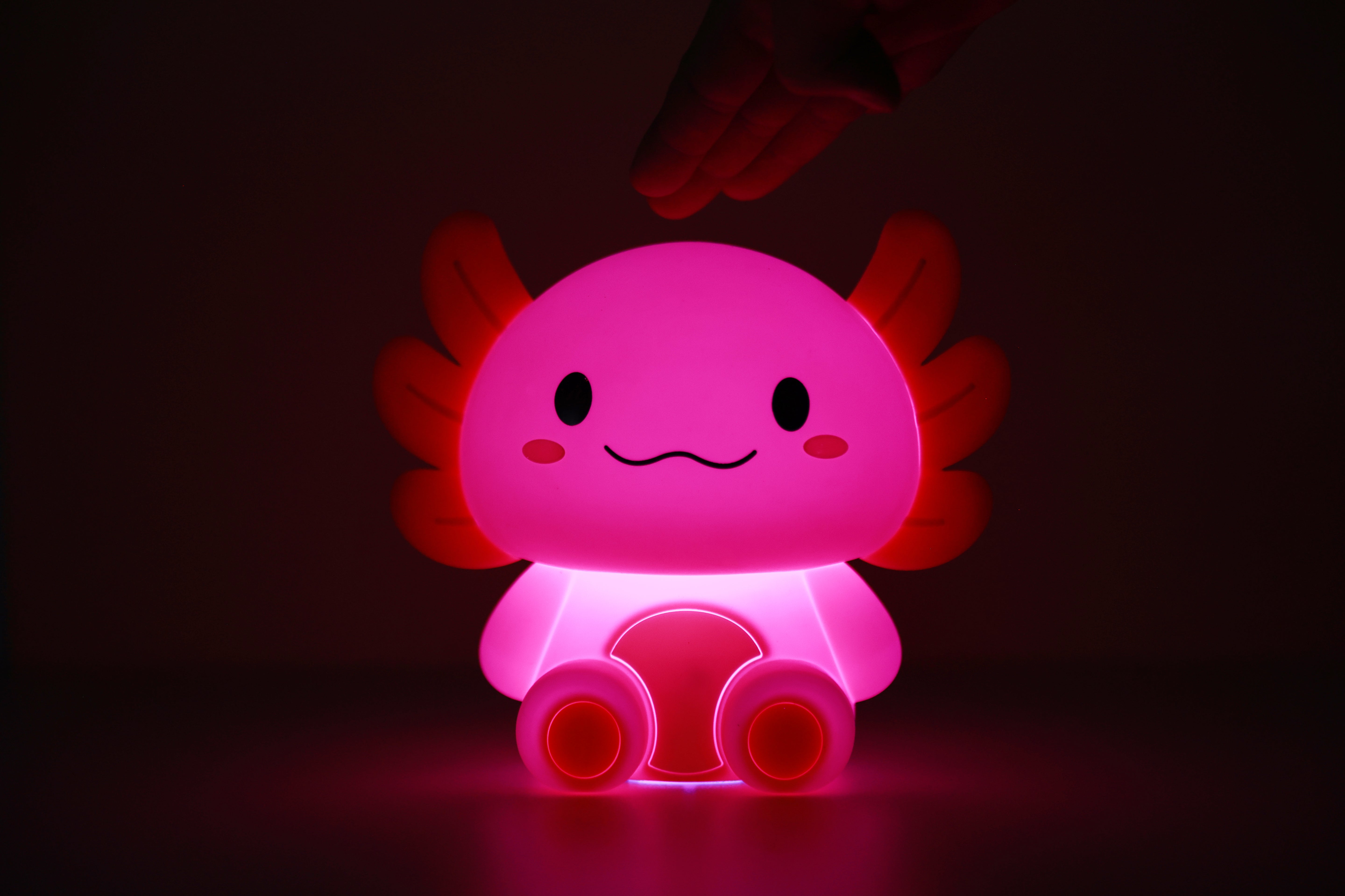 Pink leuchtendes iTotal Axolotl-Nachtlicht aus Silikon in dunkler Umgebung.