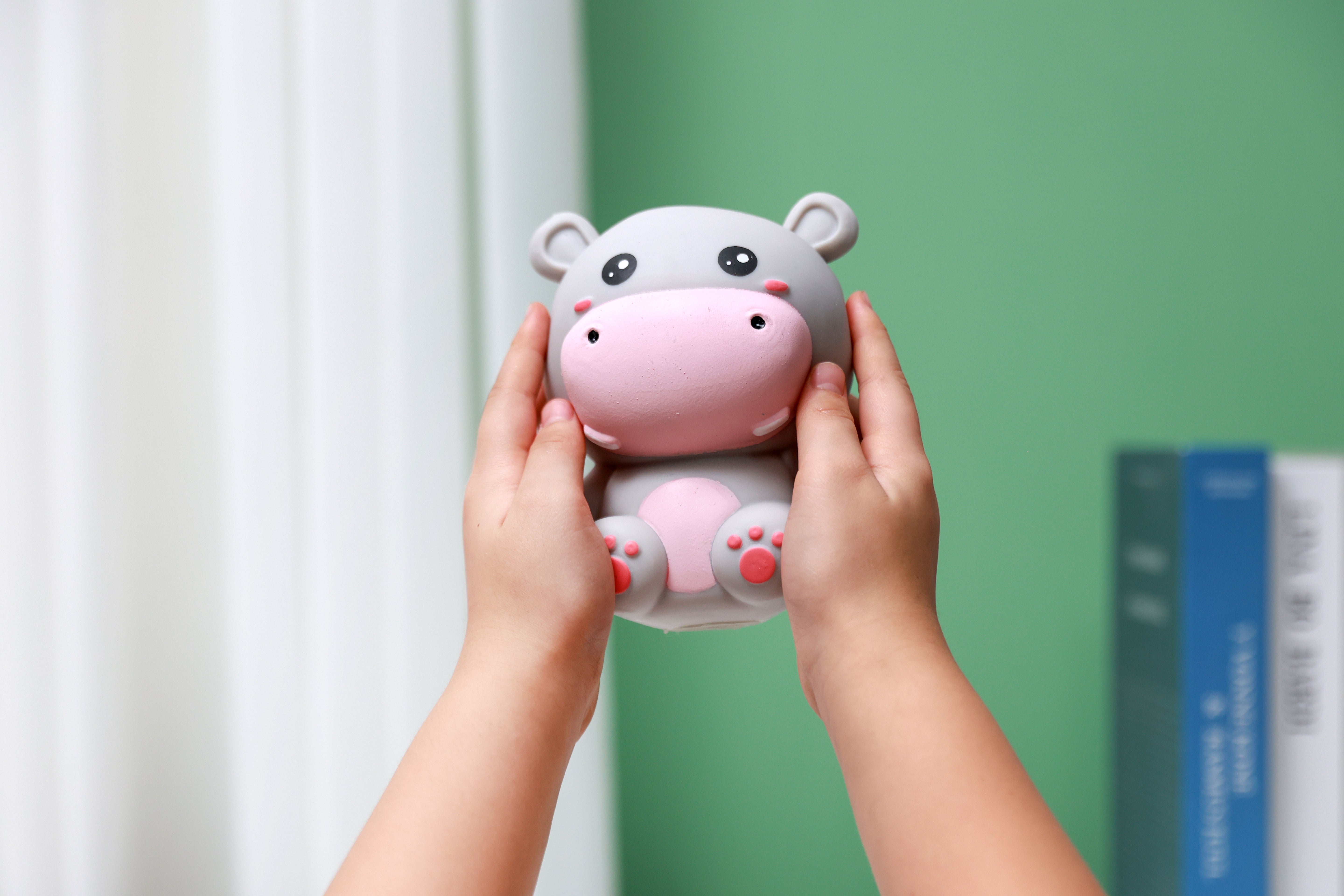 Zwei Hände präsentieren das graue iTotal Squeeze Hippo XL, ein weiches Antistress-Spielzeug mit niedlichem Gesichtsausdruck.
