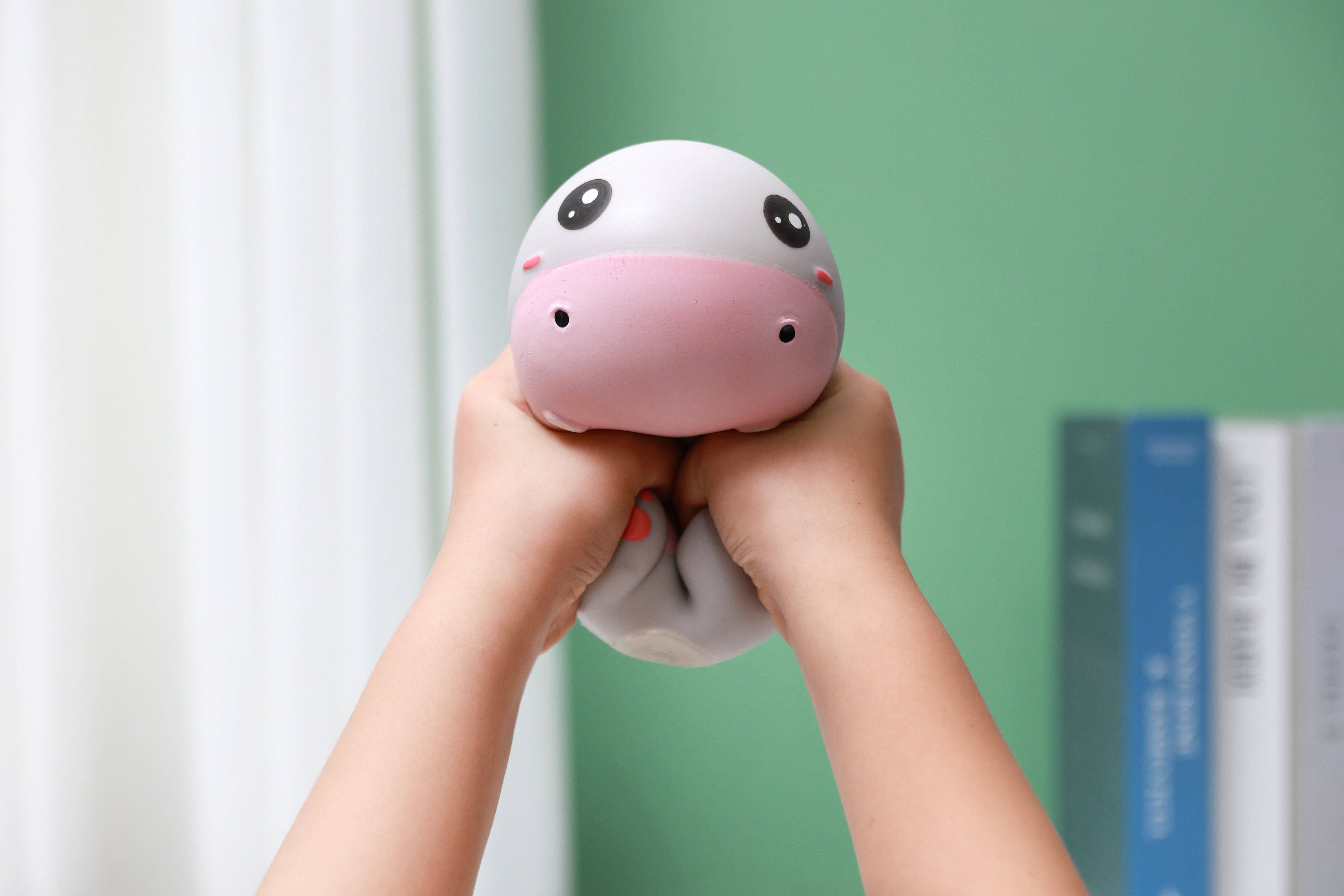 Zwei Hände drücken das graue iTotal Squeeze Hippo XL zusammen, um die weiche Antistress-Textur zu veranschaulichen.